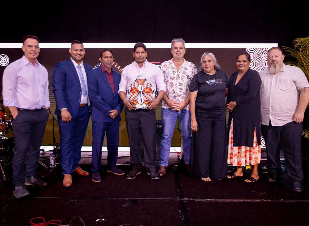 A group of seven industry delegates standing together on stage in front of event banners during a national procurement conference presentation.