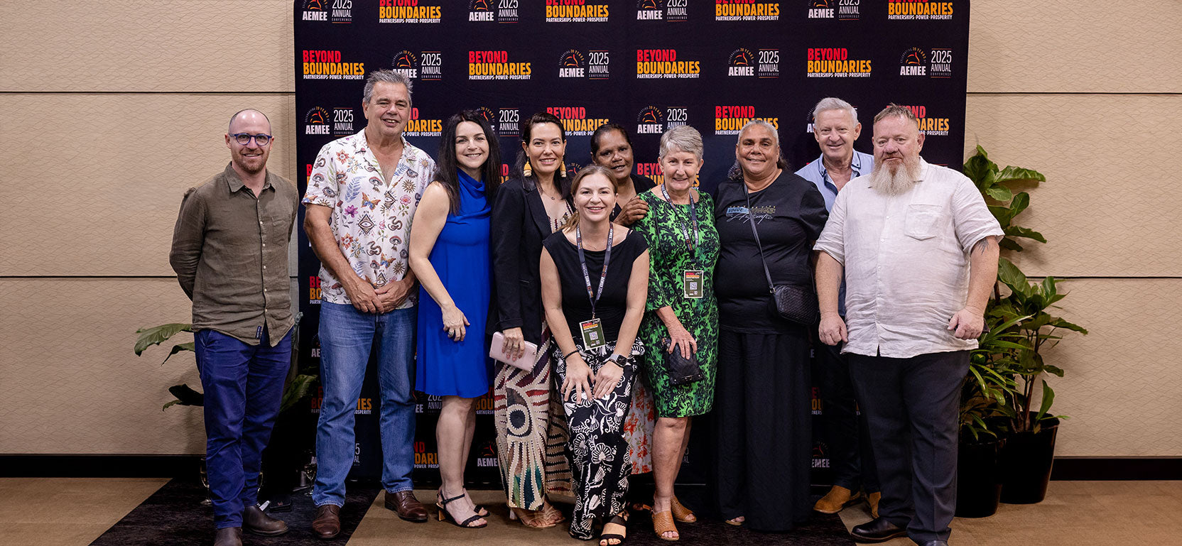 A wide group photograph of First Nations business owners, corporate executives, and board directors standing together arm-in-arm at the conclusion of an AEMEE forum.