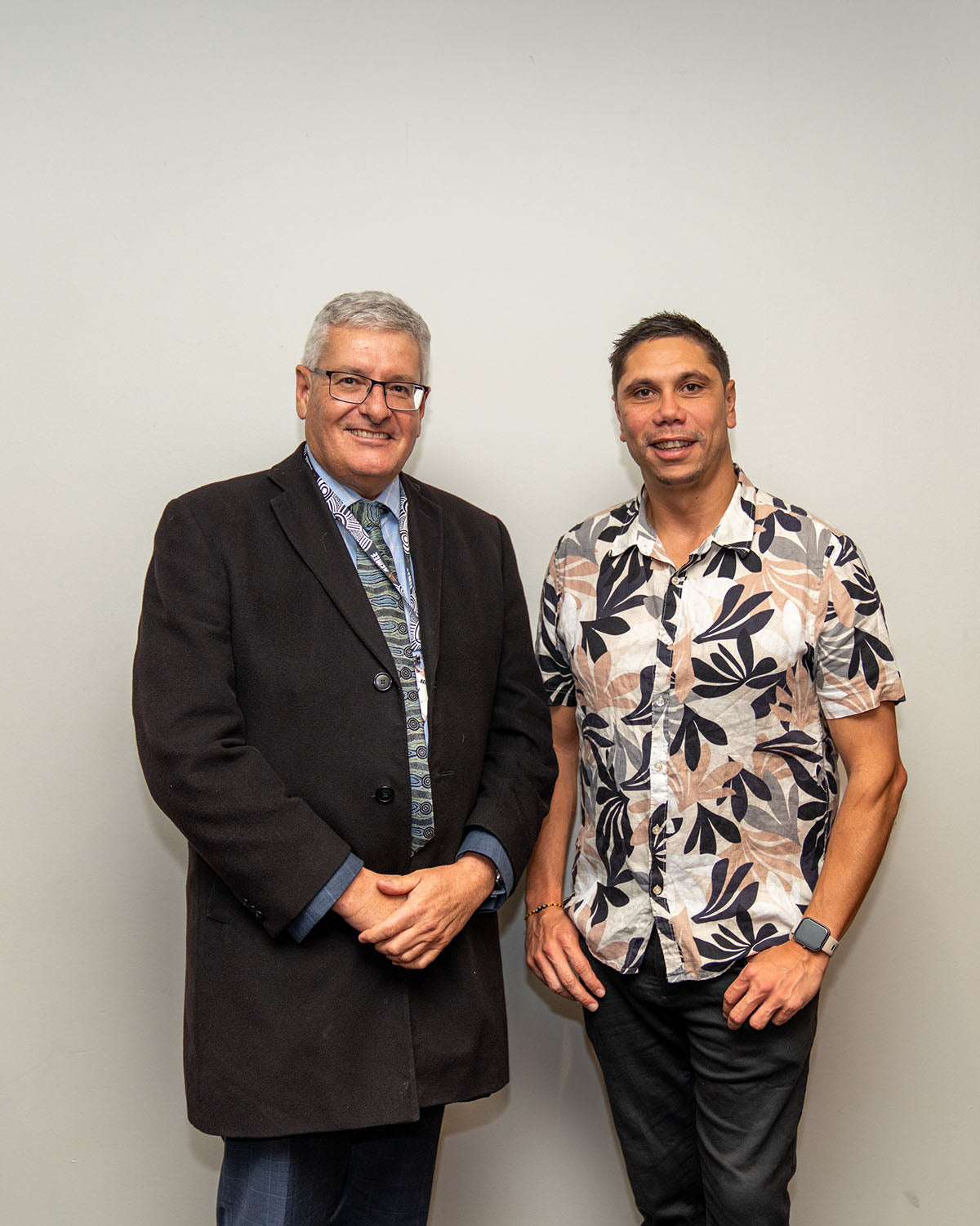 AEMEE CEO Jyi Lawton wearing a floral print resort shirt, standing alongside a keynote speaker against a clean background at the awards night.