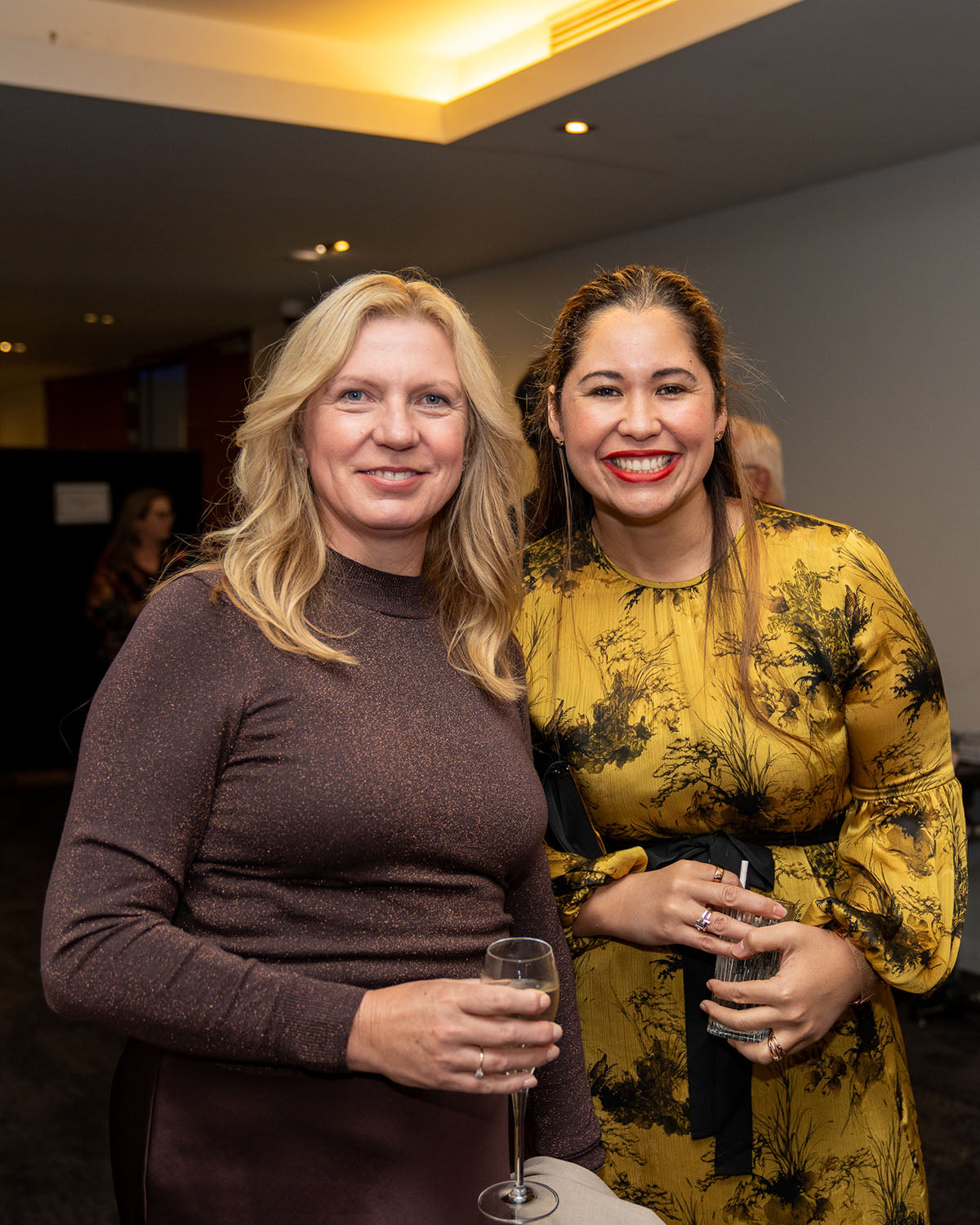 Two female delegates in evening wear smiling warmly together during the networking cocktail hour at the 17th Annual AEMEE Awards Night.
