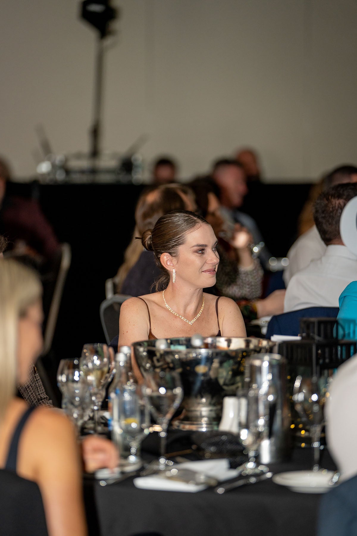 A candid over-the-shoulder view of guests seated at tables inside the main banquet hall during the awards night dinner.