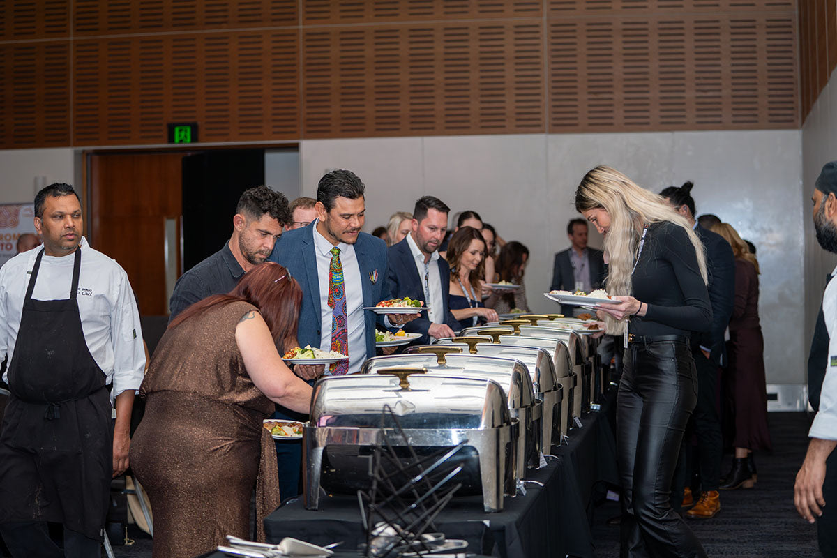 Delegates standing in line at the commercial buffet chafing dishes during the dinner service section of the conference gala.
