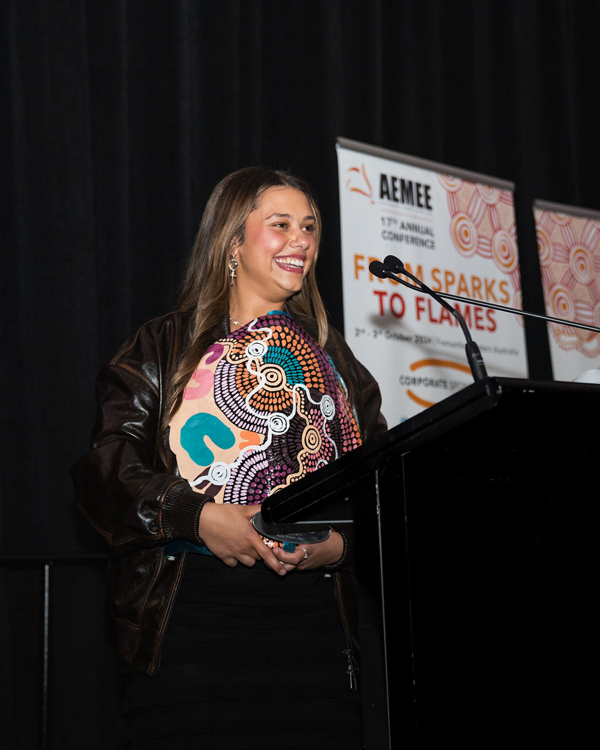 A close-up profile view of the female Waru Vehicle Hire representative smiling at the podium while celebrating their win for 2024 New Indigenous Business of the Year.