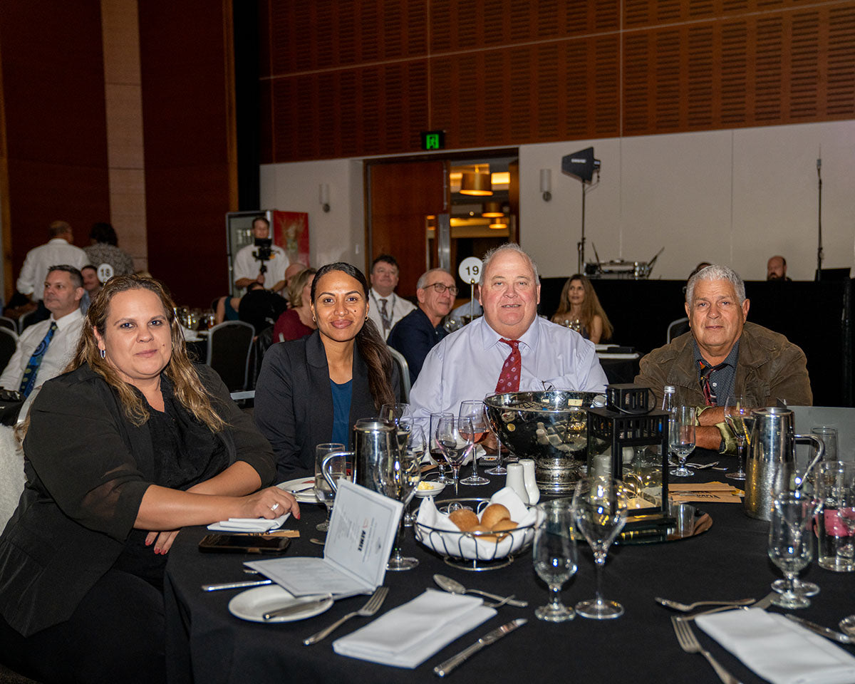 A group of four industry representatives posing together at their dressed banquet table during the 17th Annual AEMEE Awards Night.