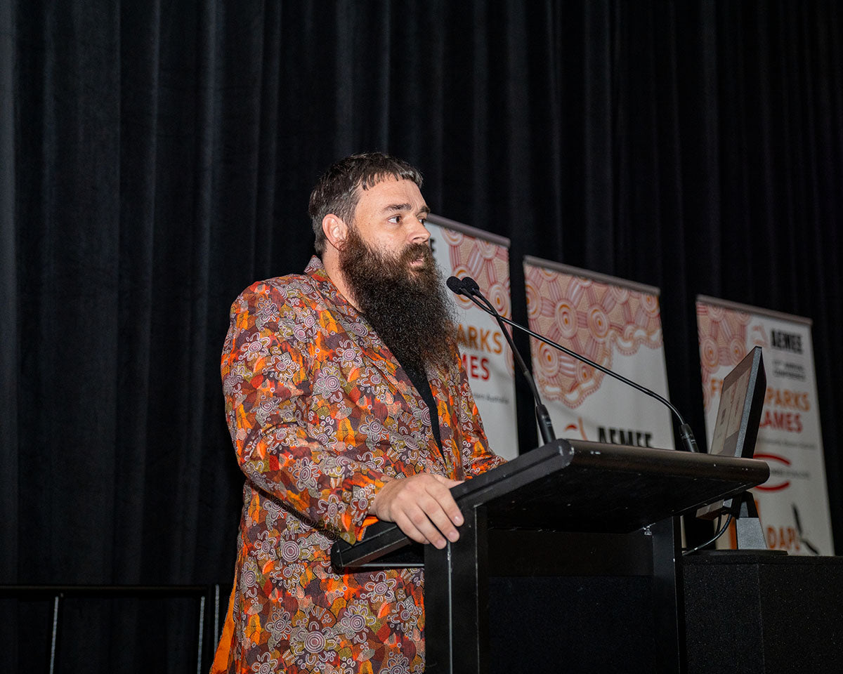 The bearded representative from BlackRock Industries speaking into the microphone at the stage podium during his official category acceptance speech.