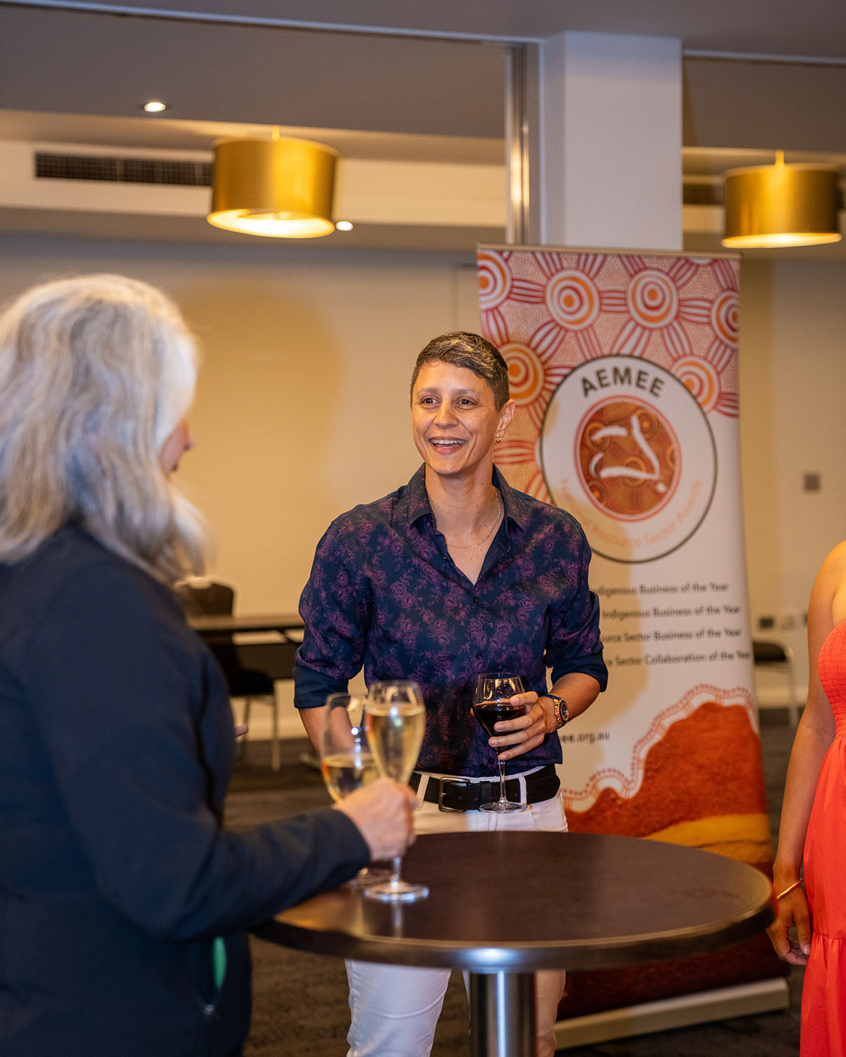 A close-up of delegates smiling and catching up near the official AEMEE National Resource Sector Awards banner before the main event doors open.