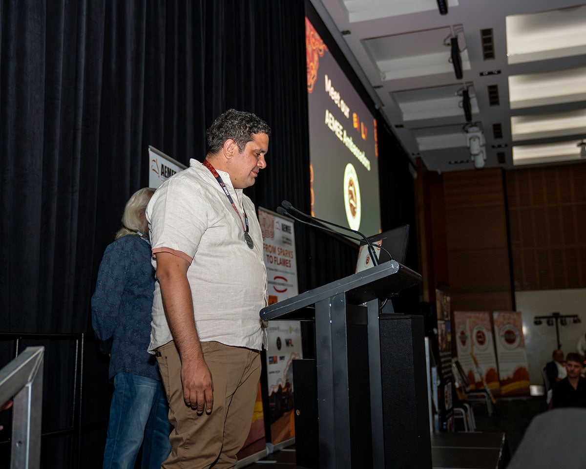 A profile shot of an industry delegate standing at the stage podium to speak before the audience in the main auditorium.