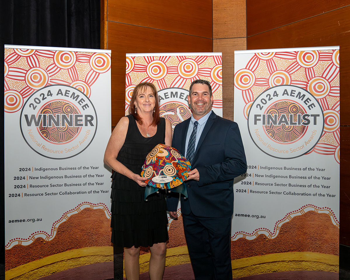 Representatives from Chevron standing together in front of the media backdrops, holding up their custom hand-painted dot-art trophy shield for 2024 Resource Sector Business of the Year.
