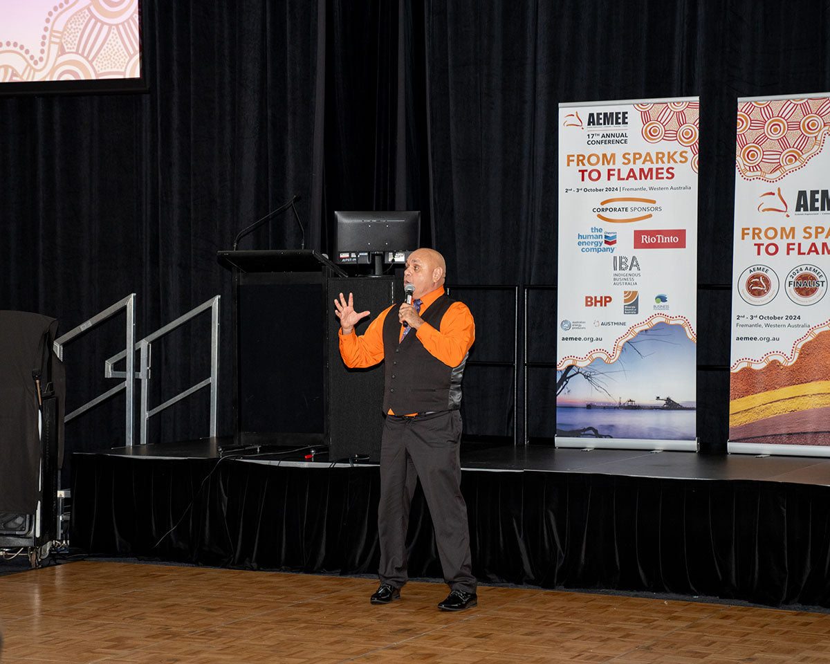 Indigenous comedian Kevin Kropinyeri gesturing dynamically and entertaining the crowd on stage during his headline performance at the 17th Annual AEMEE Awards Night.