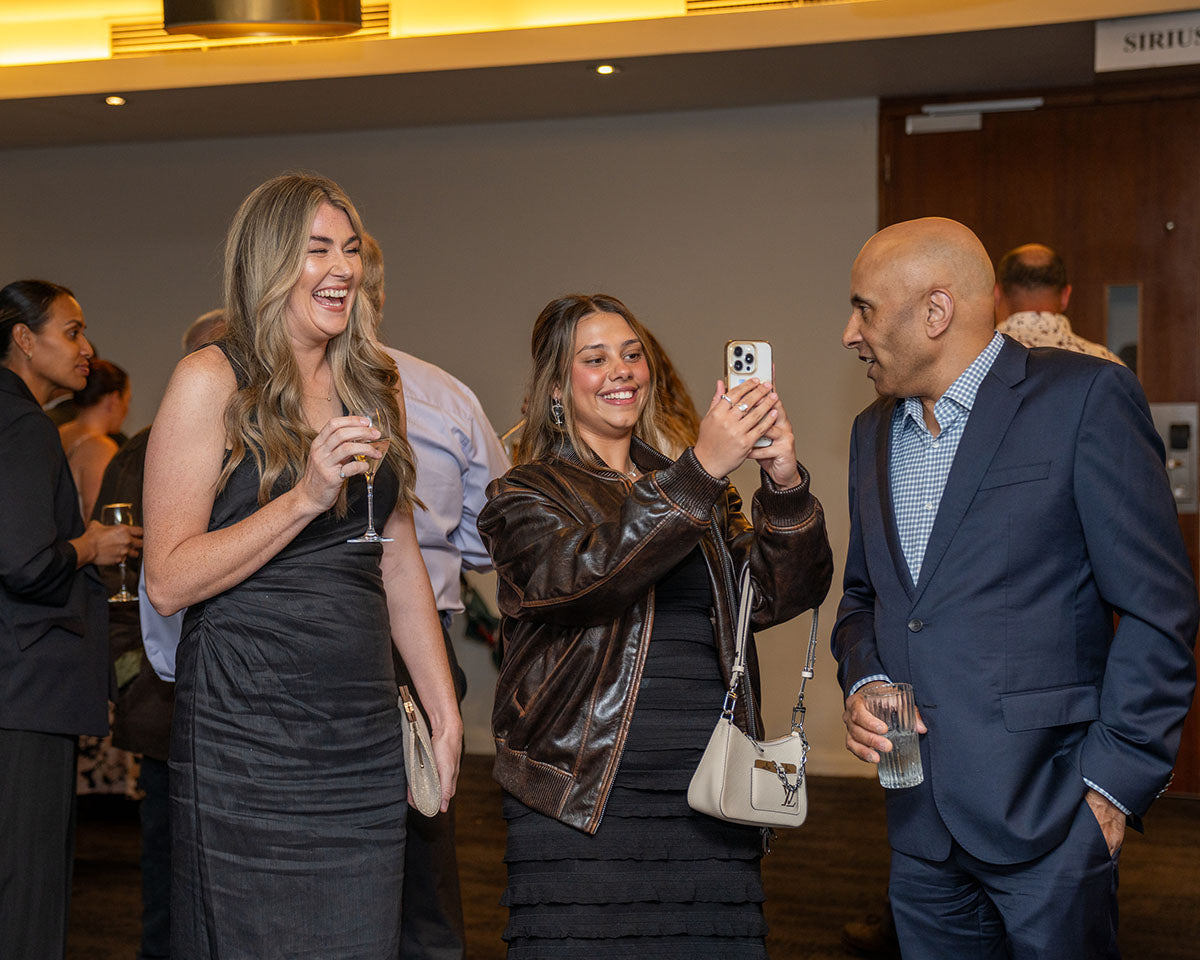 Delegates laughing and taking photos on a smartphone during the pre-dinner arrivals block of the 17th Annual AEMEE Awards Night.