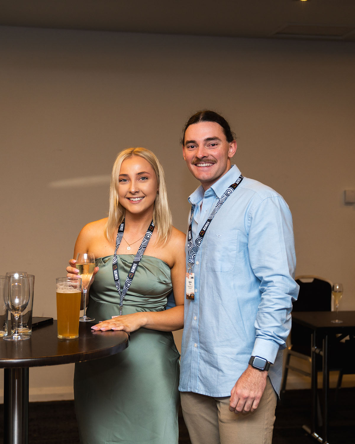 A young male and female industry delegate smiling together in the function room reception area before the awards banquet dinner.