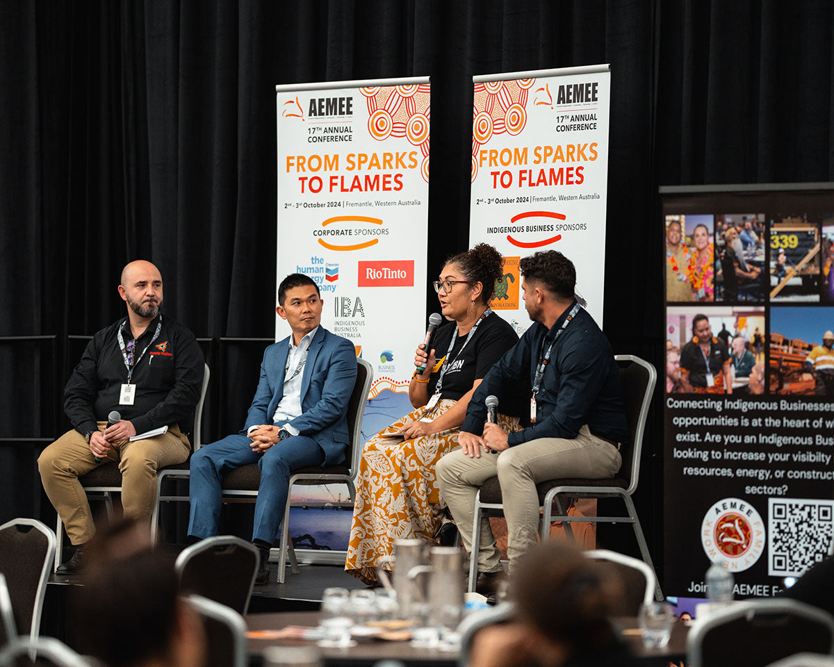 Four panel speakers engaging in a live discussion with conference delegates from the main stage auditorium layout at the annual national AEMEE conference.