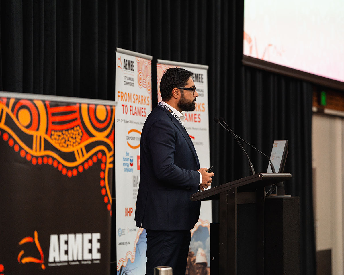 Gohar Rhind from the Waalitj Foundation standing at a stage podium in a dark suit, presenting on core industry frameworks at the 2024 AEMEE conference.