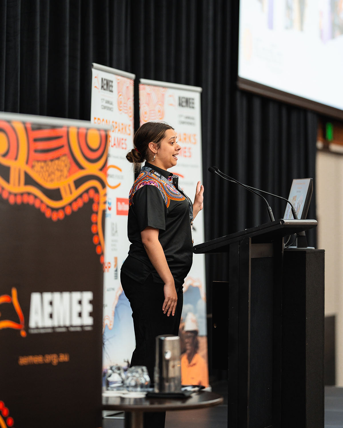 A presenter speaking from the microphone during an interactive technical stream panel exploring strategic opportunities in the Indigenous business resources sector. industry leader gesturing during her stage presentation, highlighting growth frameworks within the Indigenous business resources sector.