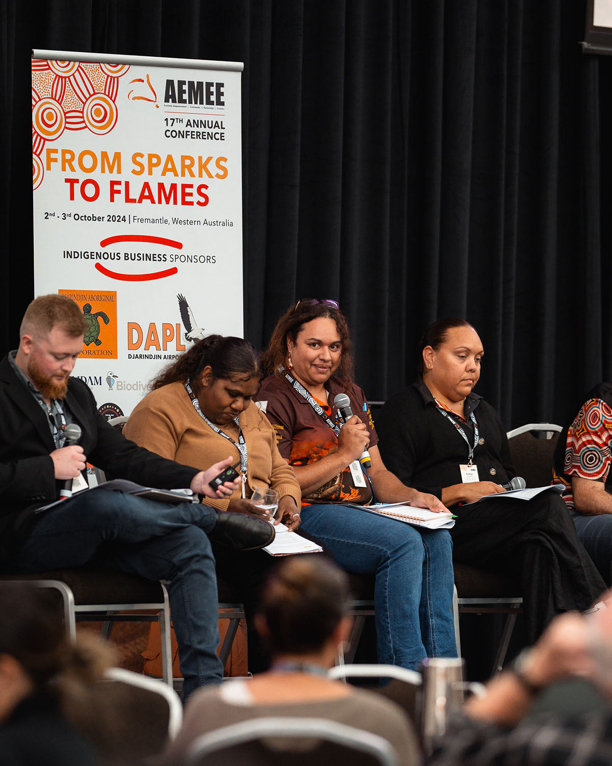 Female panelists presenting on stage under corporate and community banners tracking development paths for the Indigenous business resources sector.