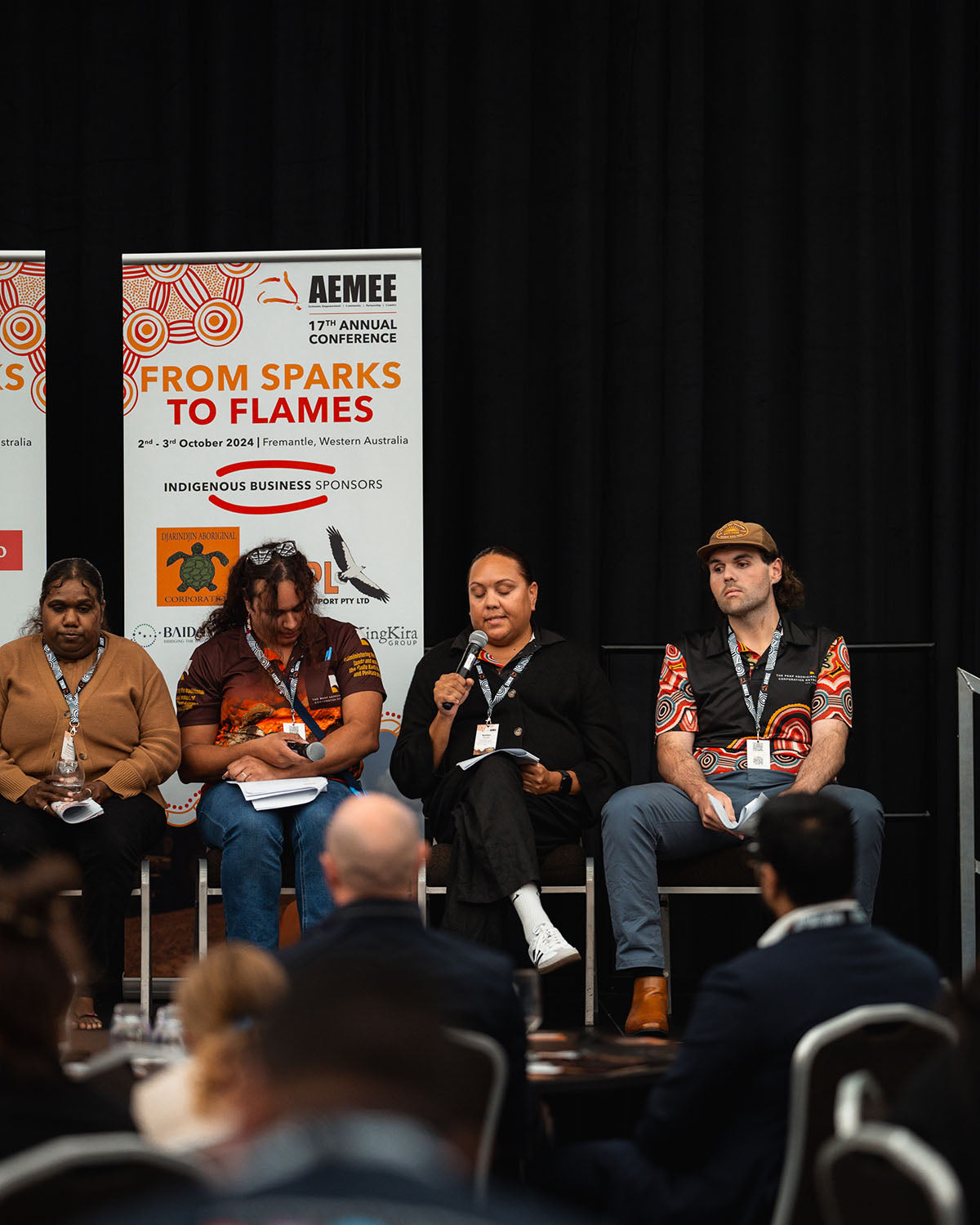 Four seated panel speakers addressing the audience during a live question-and-answer session at the annual AEMEE conference.