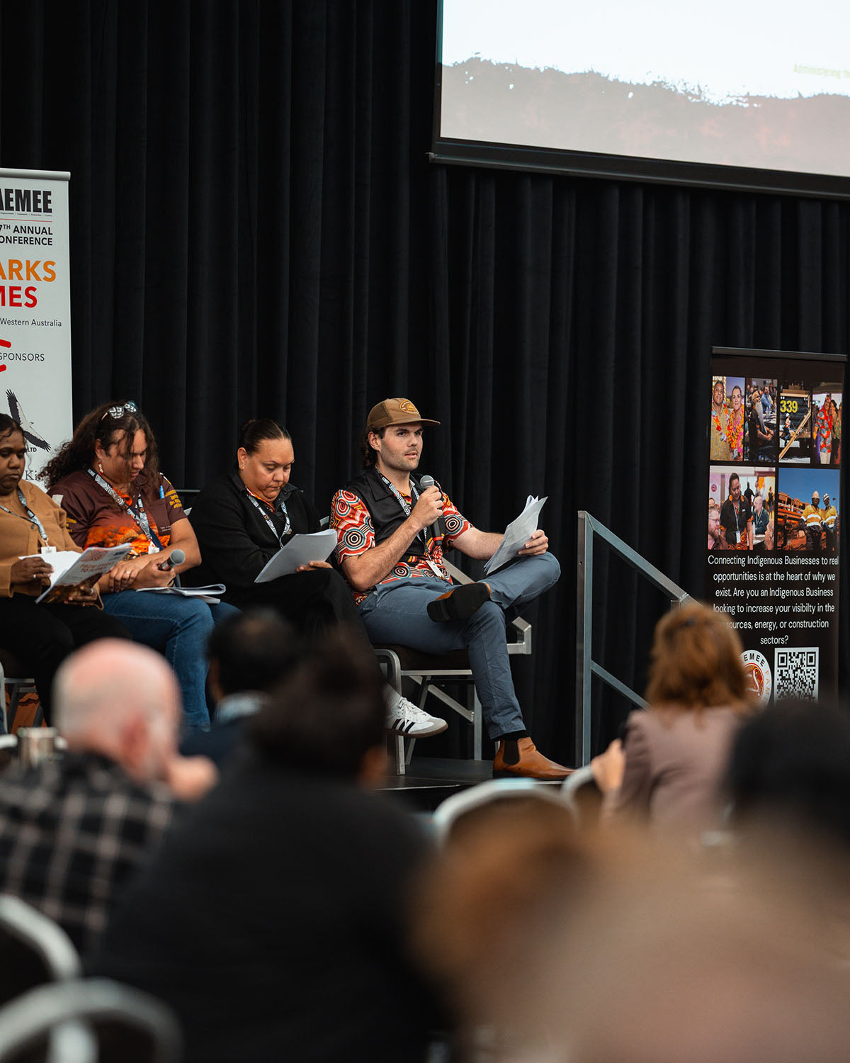 A side perspective of stage presenters and panelists speaking to delegates about growth within the Indigenous business resources sector.