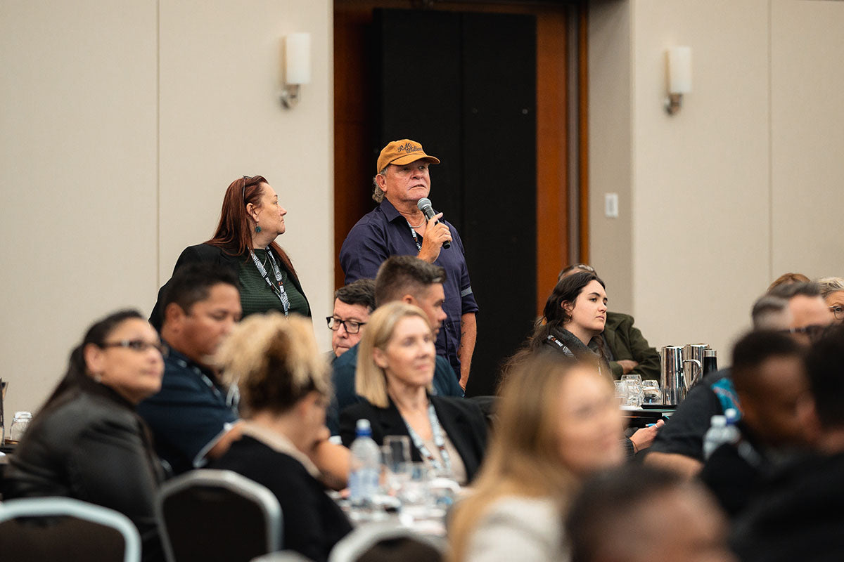 An audience delegate stands up with a microphone to ask a question during an interactive industry Q&A panel session at the AEMEE conference.