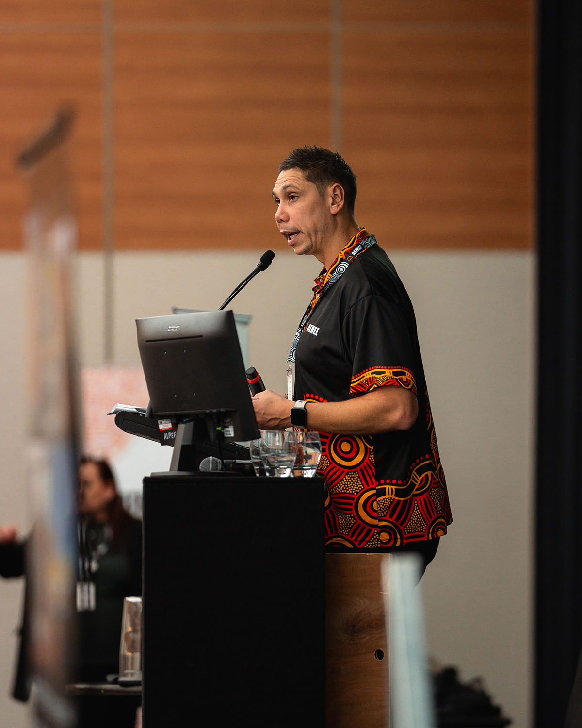 Jyi Lawton presenting at the main stage microphone during a major corporate plenary session at the annual national AEMEE conference.