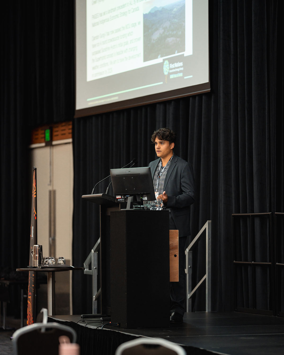 A young presenter standing at the stage microphone during a dedicated technical stream presentation for the Indigenous business resources sector.