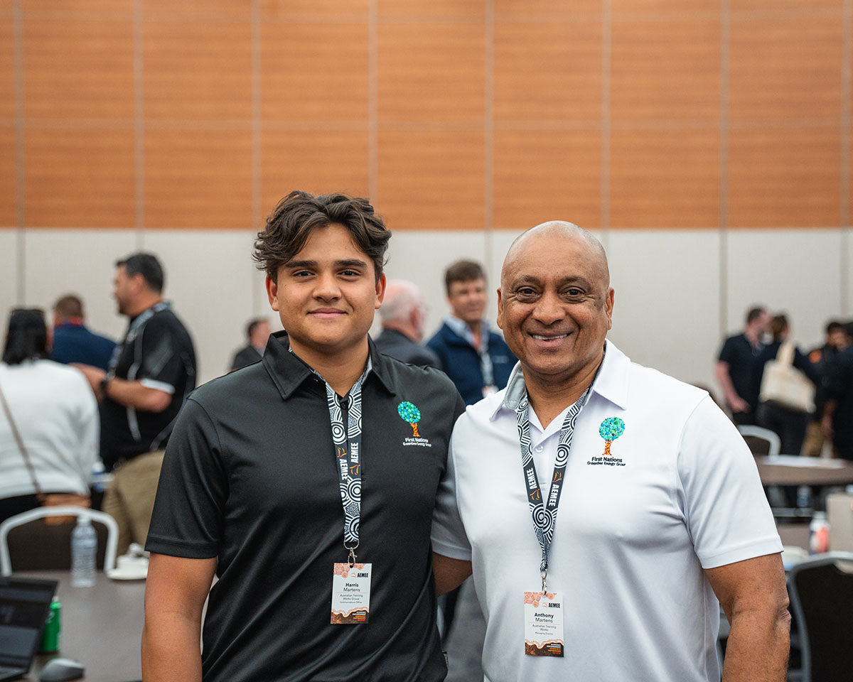 Two male corporate partners smiling together alongside other attendees inside the main hall during the closing networking block of the 17th Annual AEMEE conference.