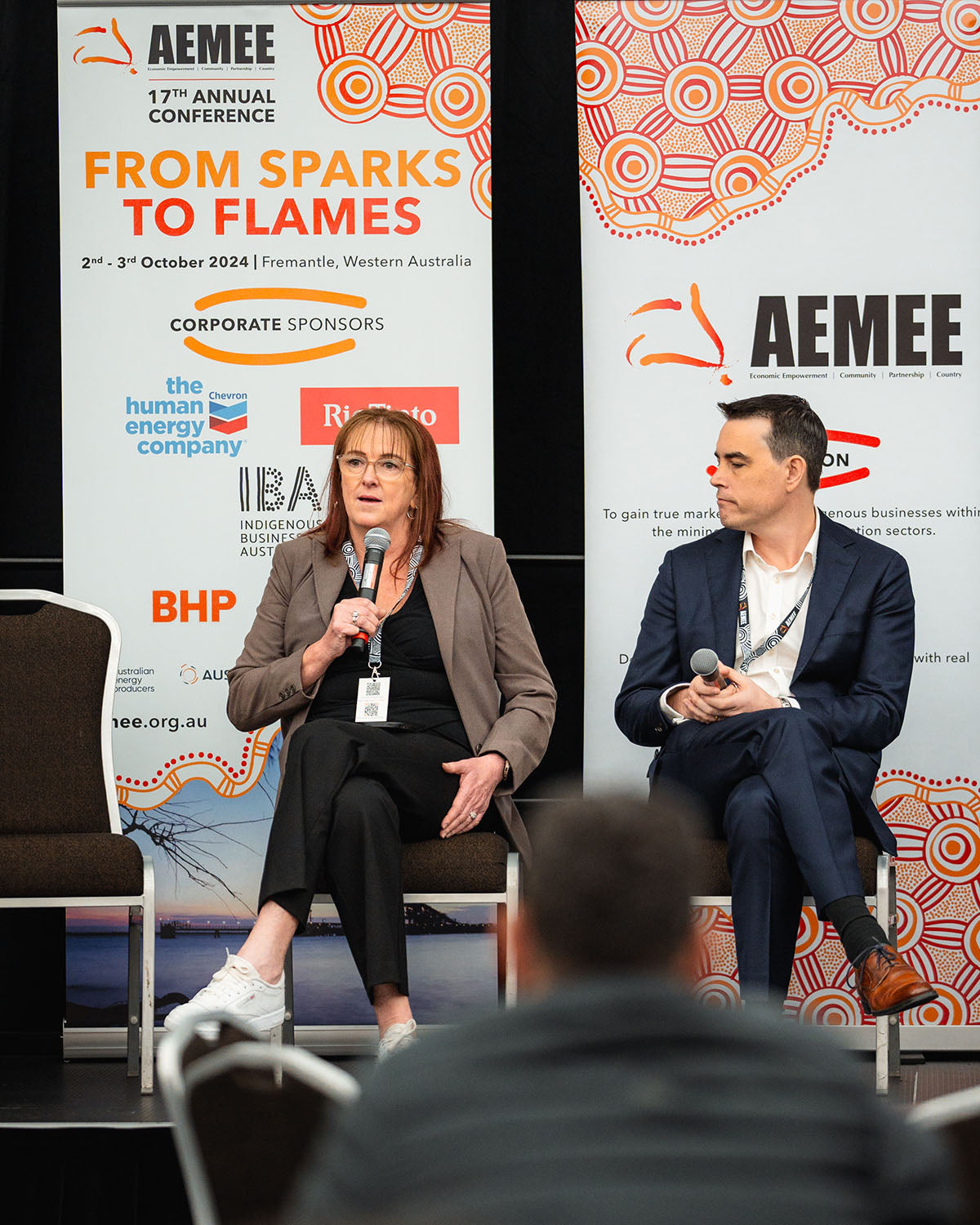 Seated industry panel speakers addressing delegates in front of BHP, Chevron, and Rio Tinto corporate sponsor banners at the AEMEE conference.