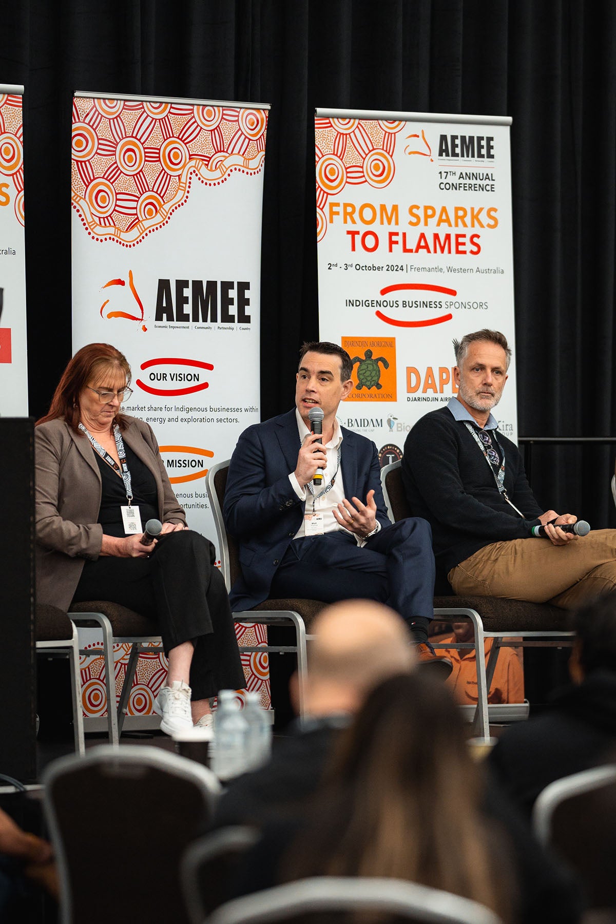 Rio Tinto's Matt Plichta speaking from the stage panel under official AEMEE vision and mission graphics, highlighting procurement pathways within the Indigenous business resources sector.