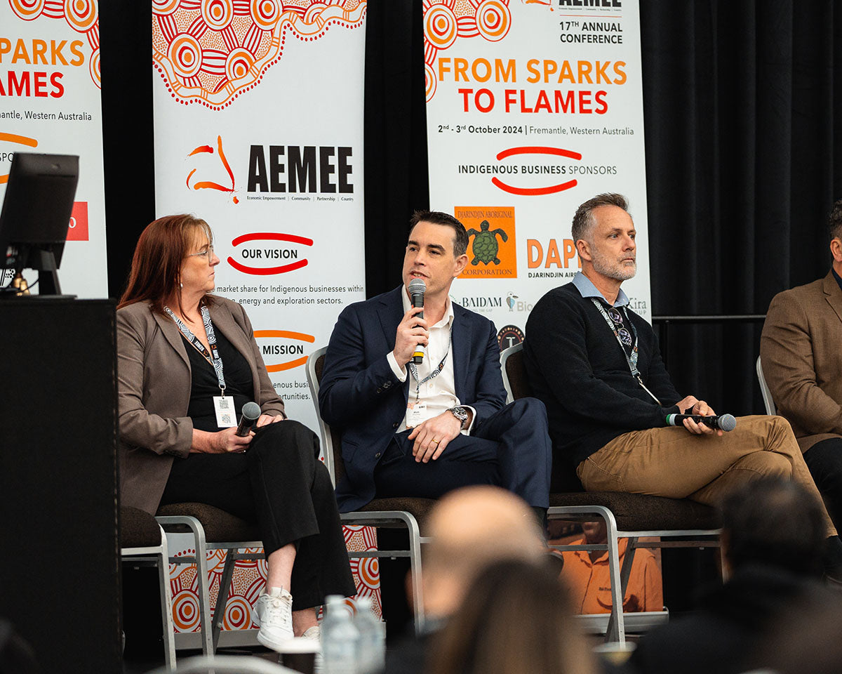 Matt Plichta from Rio Tinto speaking into a microphone while seated on an interactive resource panel at the annual AEMEE conference.