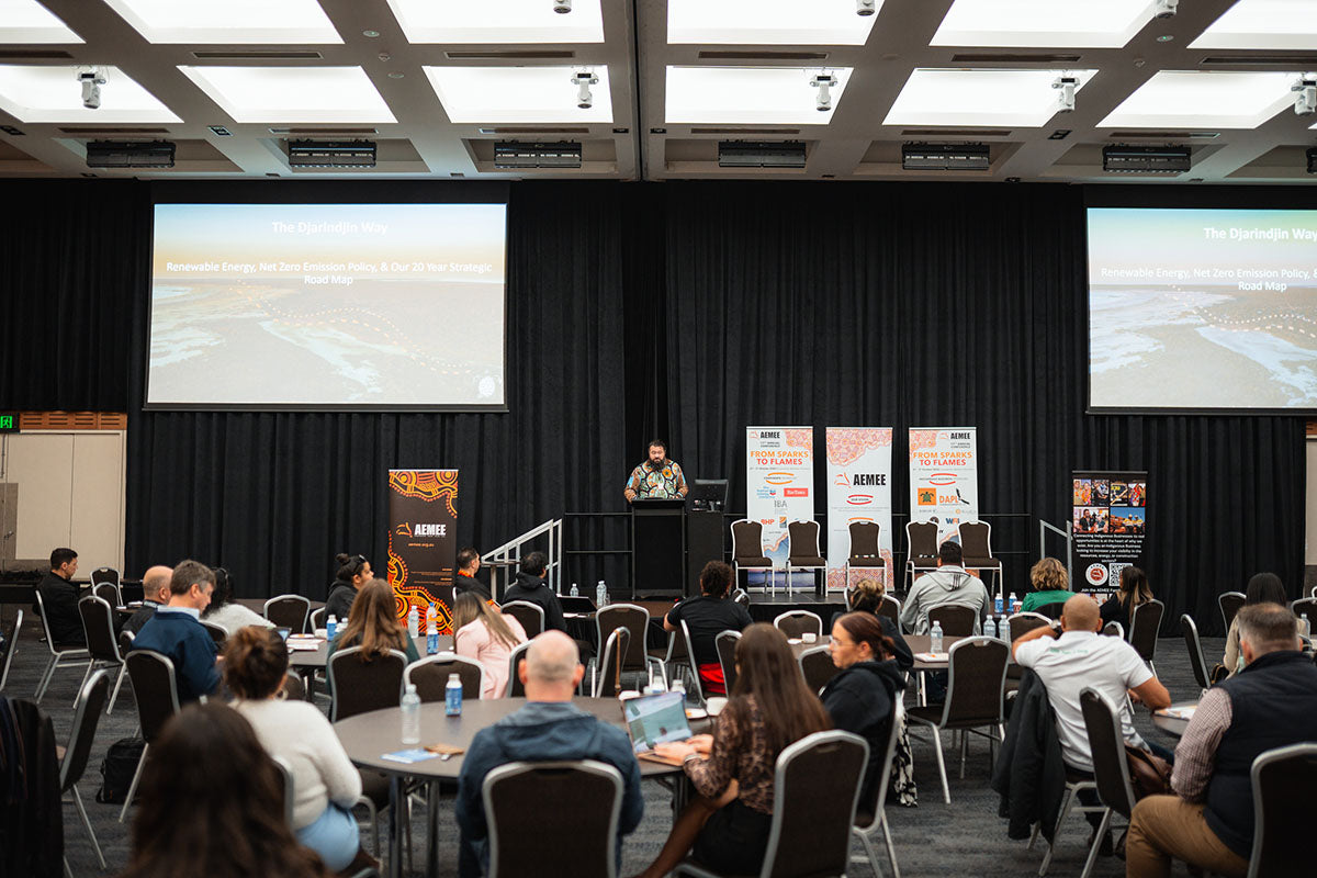 A wide view of the AEMEE conference hall showing delegates watching Nathan McIvor's presentation beneath a projection screen detailing the 20 Year Strategic Road Map.