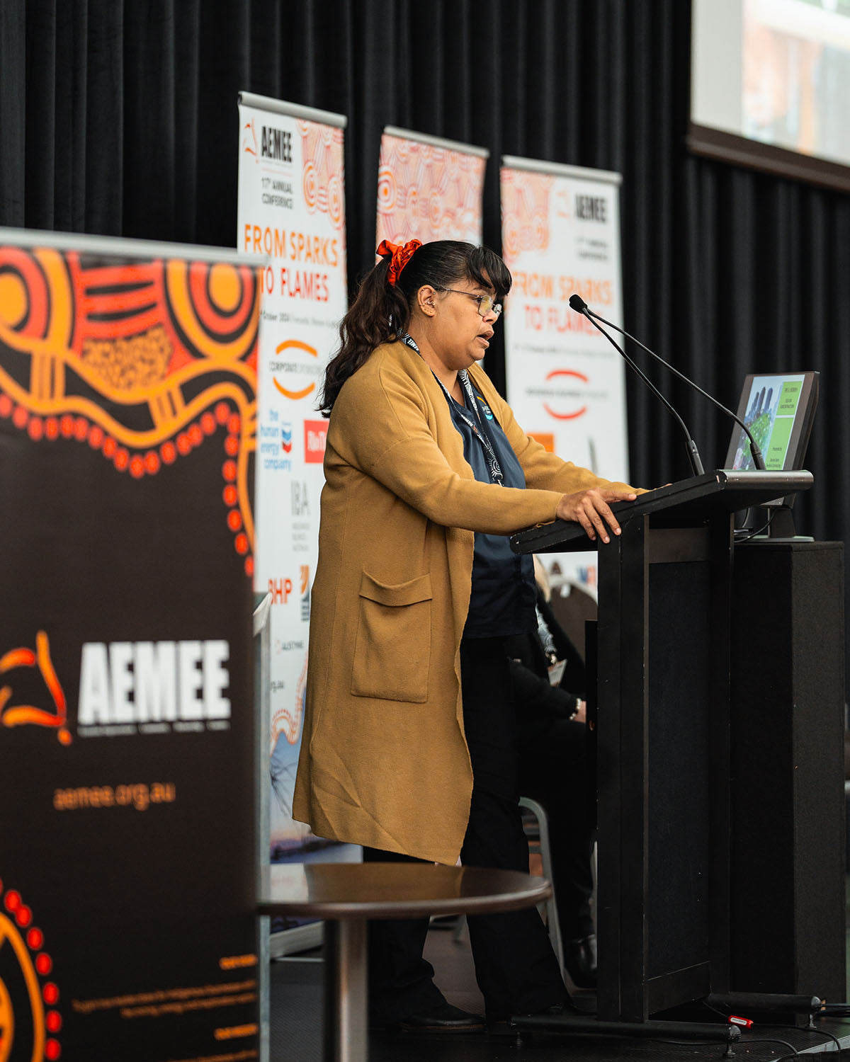 A close-up view of Sherlock Contracting's Denise Stan at the stage podium, discussing industry solutions within the Indigenous business resources sector.