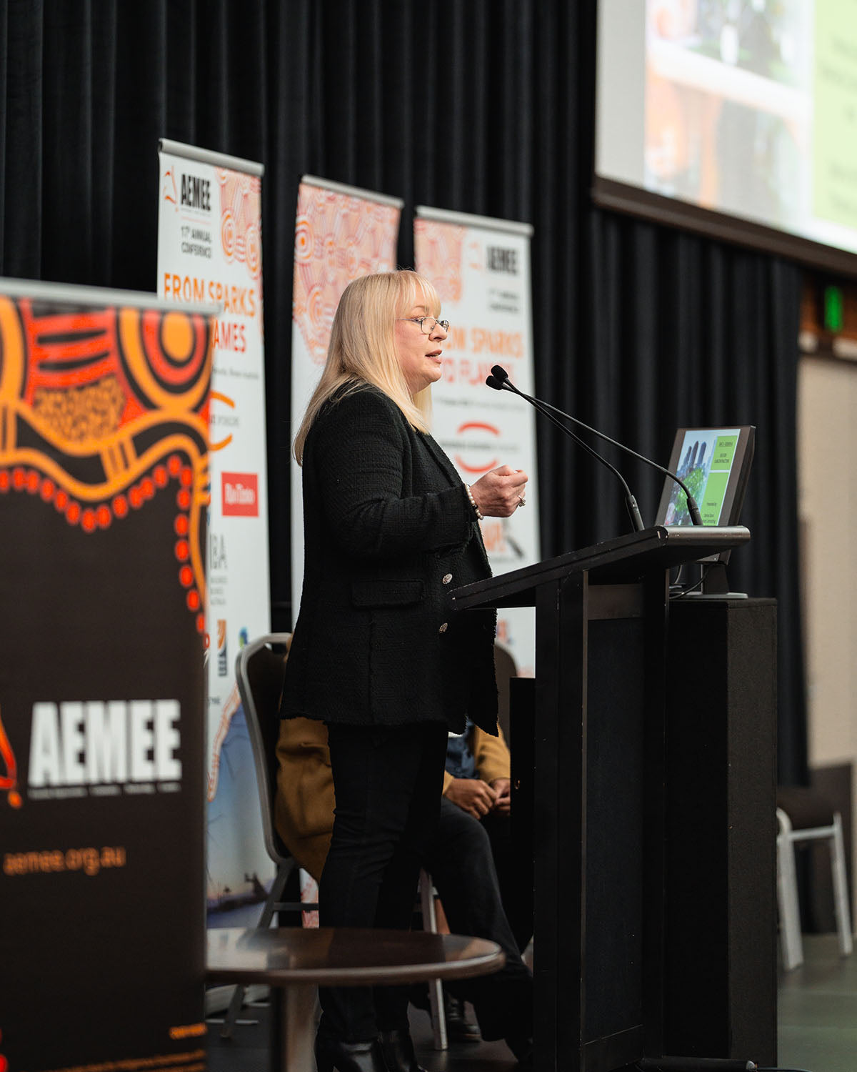 A side profile shot of blonde speaker Sabina Schlink delivering her address on commercial pathways within the Indigenous business resources sector.