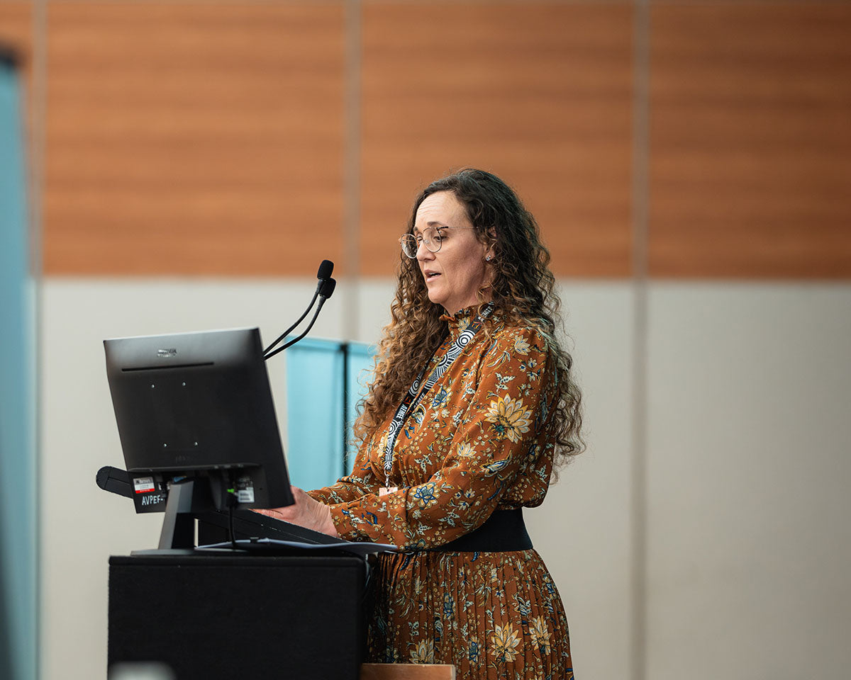 A close-up side perspective of a female keynote speaker presenting behind the stage monitor at the 17th Annual AEMEE conference.