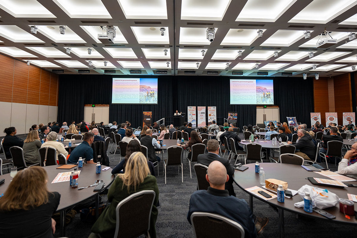 Corporate and community delegates seated around interactive tables watching a main stage keynote presentation at the annual national AEMEE conference.
