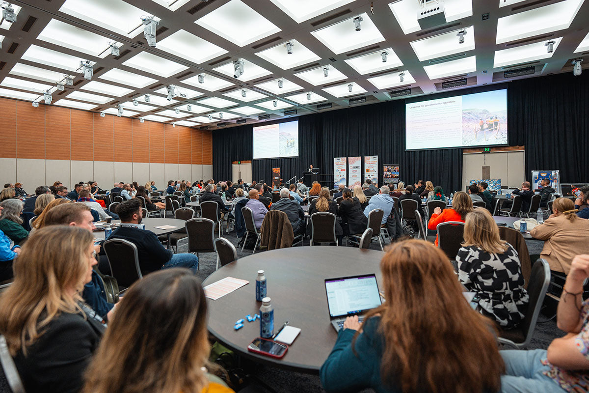 Conference attendees using laptops and taking notes at their tables during a strategic stream panel discussion focused on the Indigenous business resources sector.