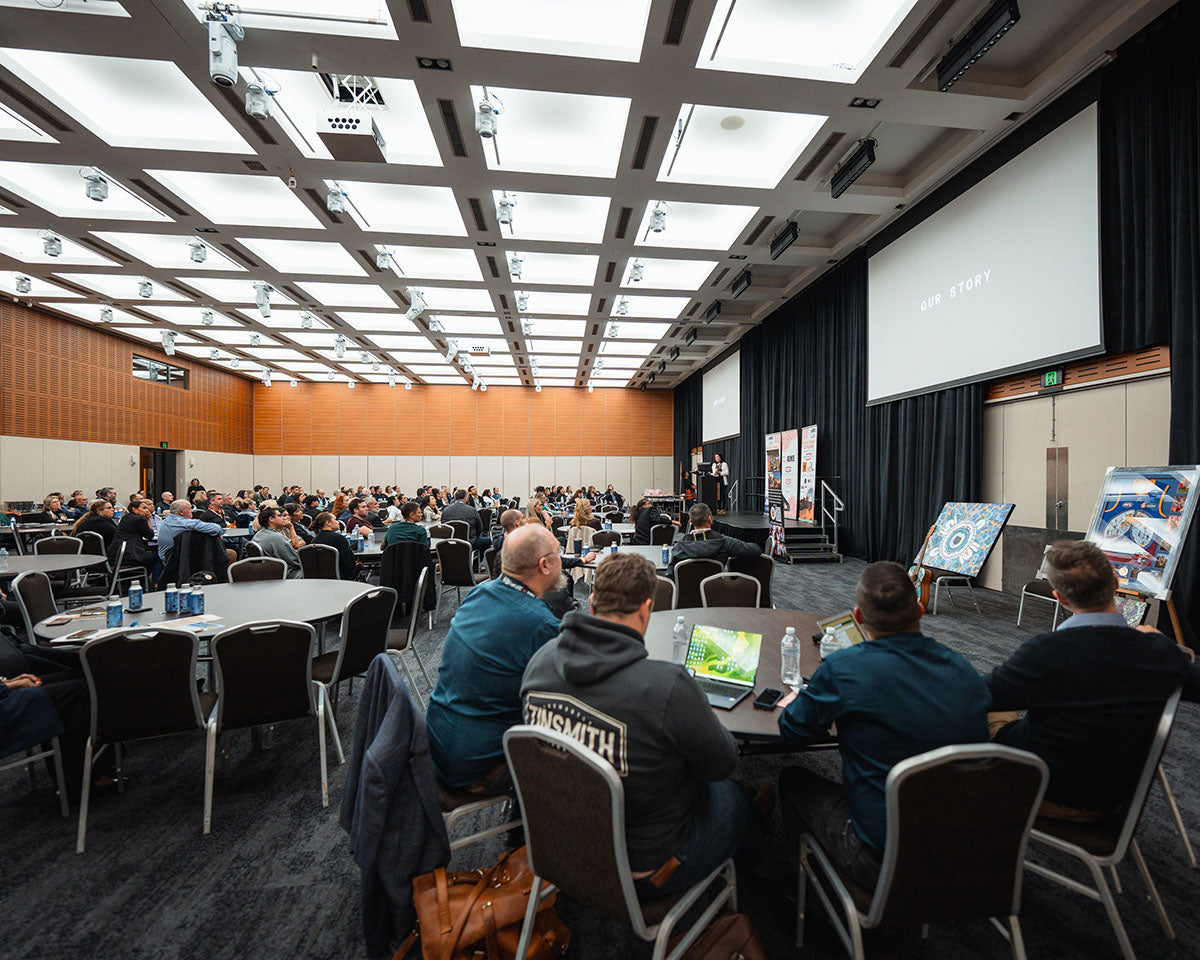Conference attendees using laptops and taking notes at their tables during a strategic stream panel discussion focused on the Indigenous business resources sector.
