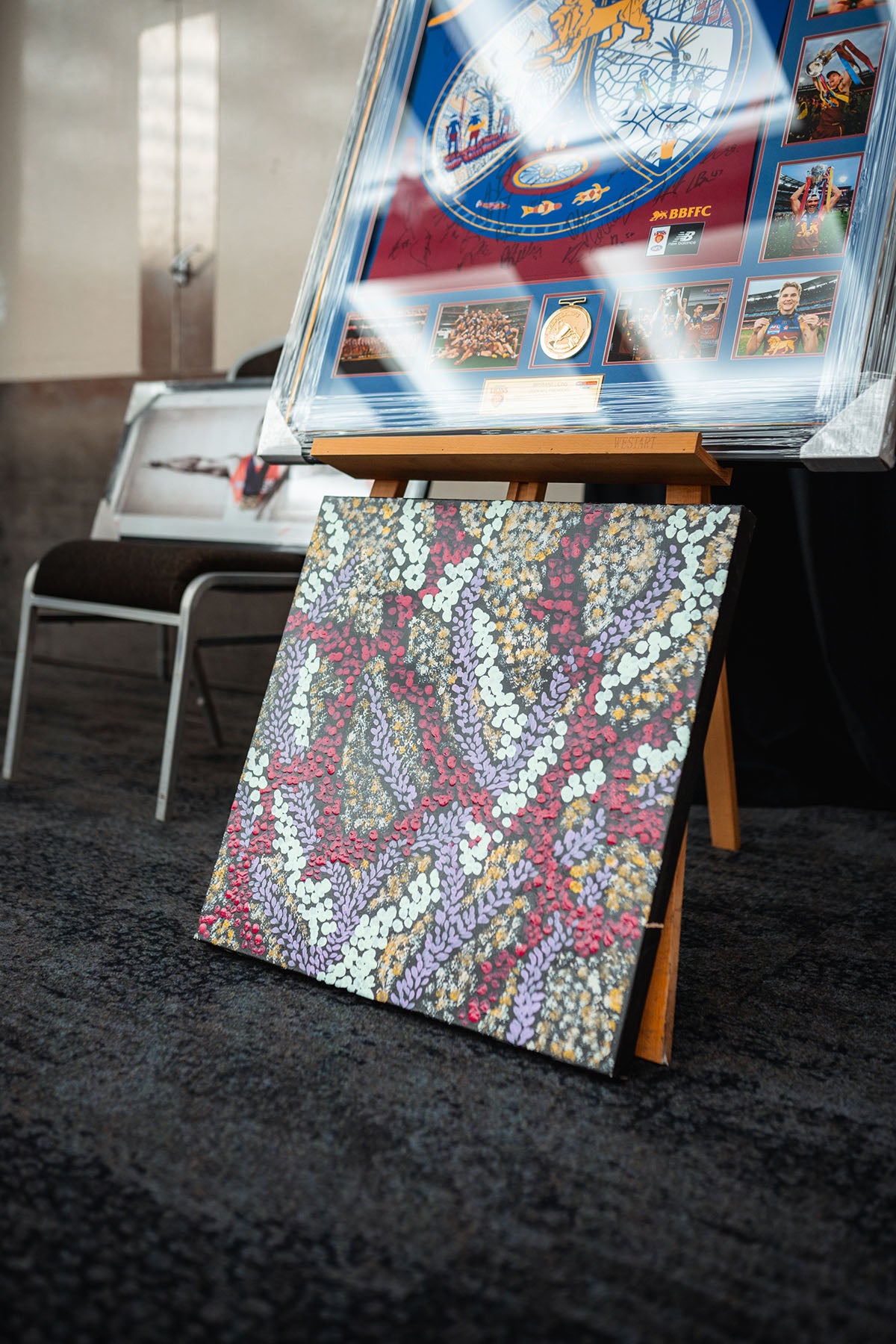 A beautiful canvas painting featuring complex traditional First Nations dot art patterns in purple, pink, and gold tones showcased at the national AEMEE conference.