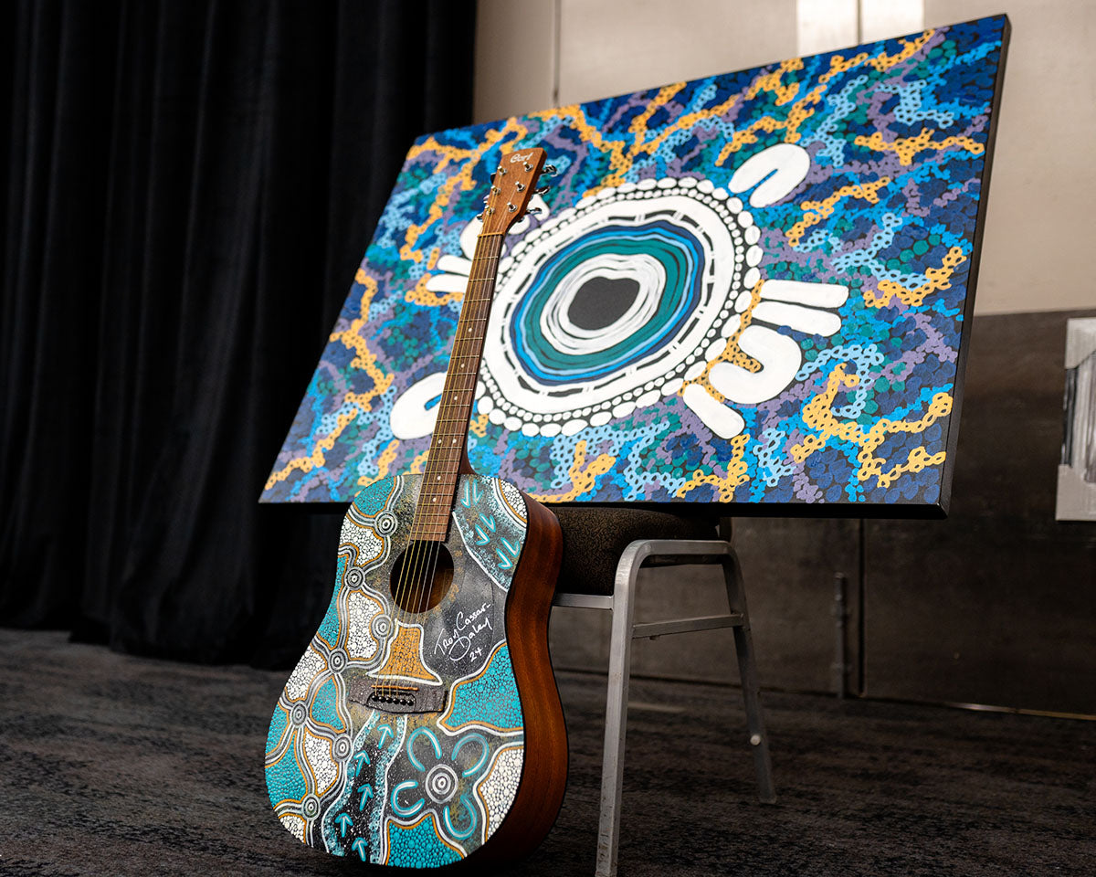 A large-scale First Nations canvas painting featuring bright blue, white, and yellow circular design patterns on display at the national AEMEE conference.
