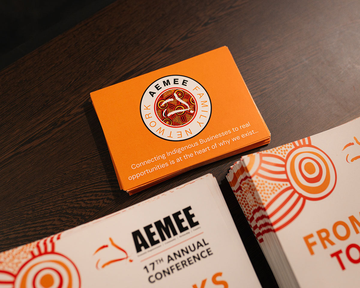 An overhead view of official 17th Annual AEMEE Conference programs and promotional booklets laid out on a dark wooden table for arrivals.