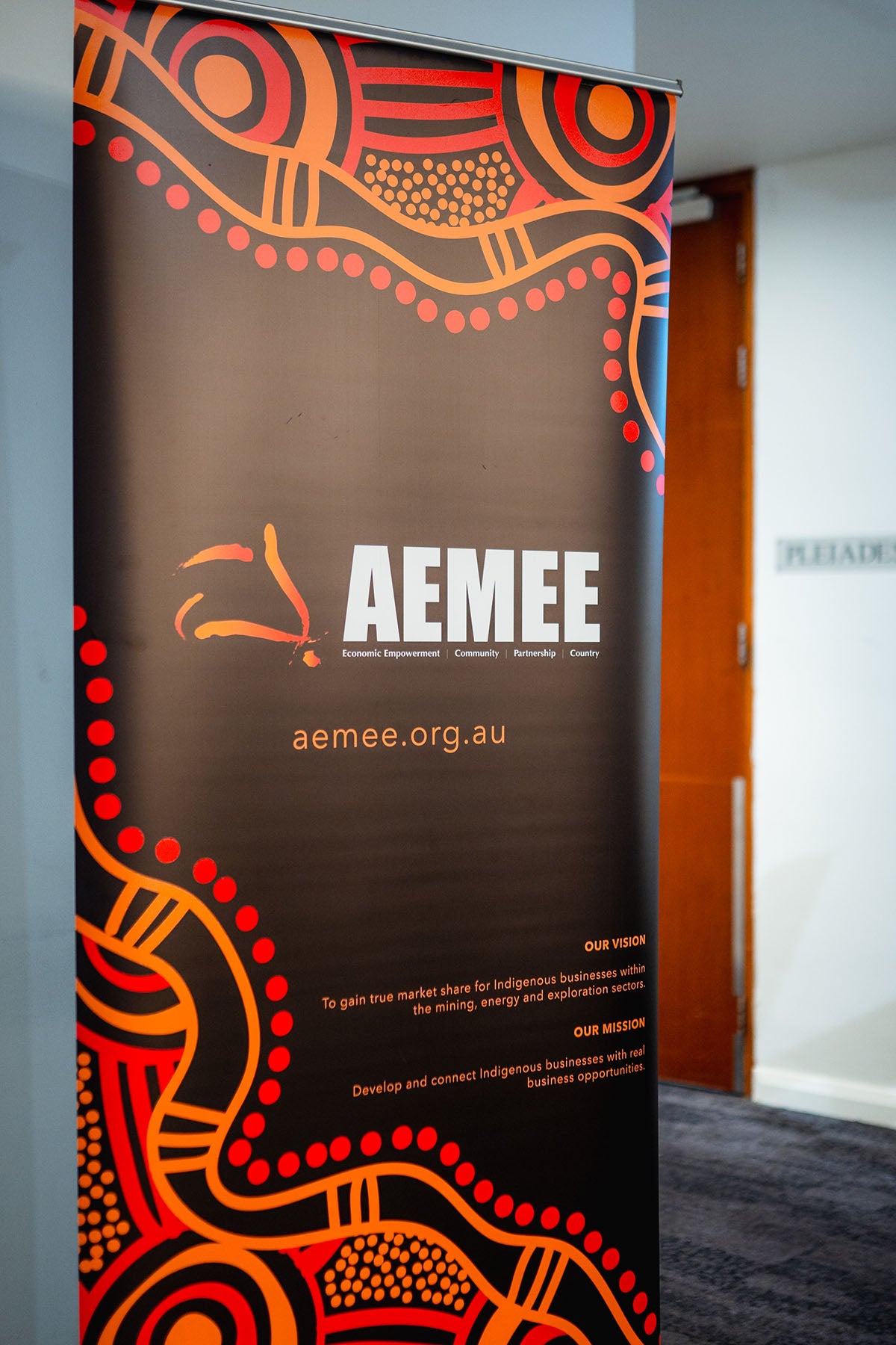 A prominent, colorful pull-up banner displaying the main AEMEE logo and traditional dot art styling outside the awards night function venue entrance.