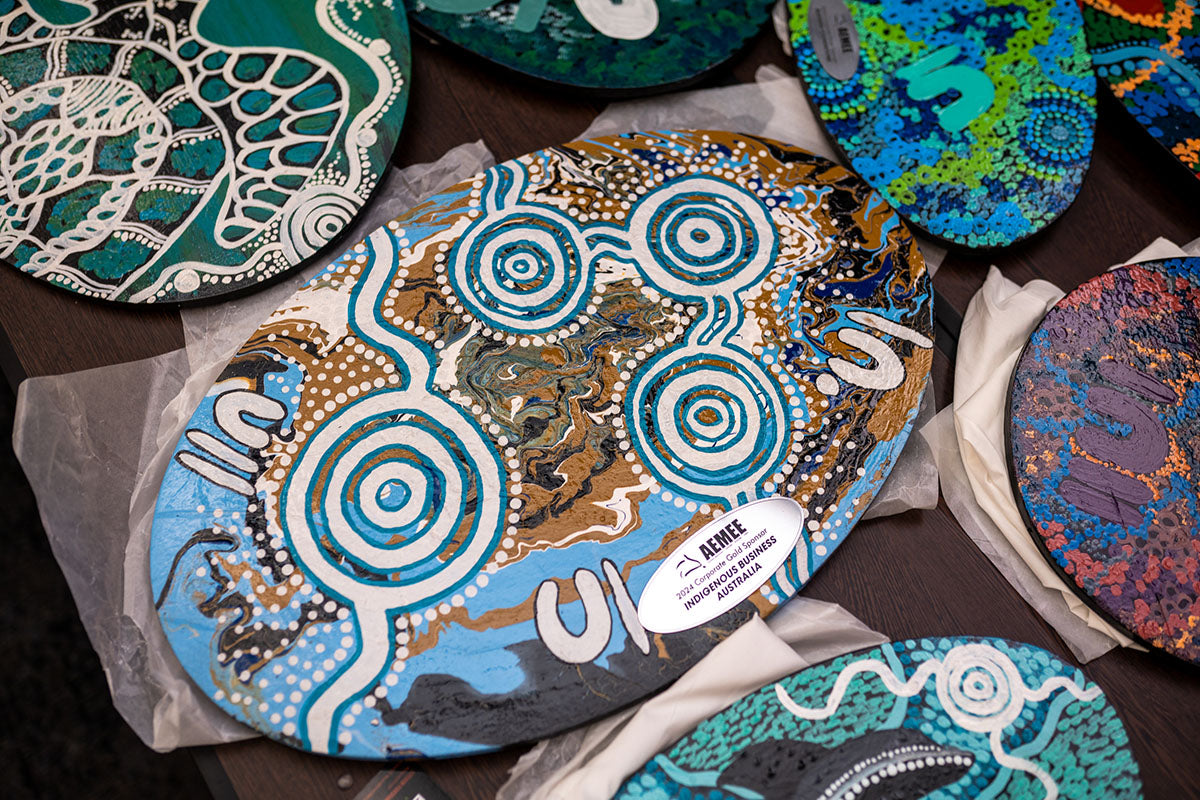 A detailed close-up of an oval-shaped AEMEE National Resource Sector Award featuring intricate blue and white traditional hand-painted dot artwork.