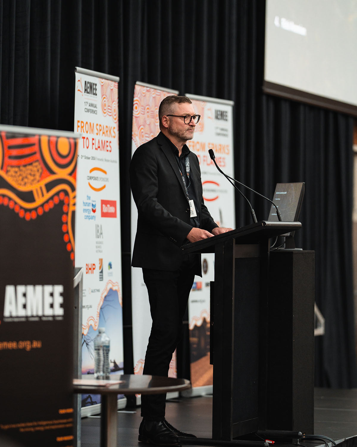 Kent Matla delivering an industry stream address from the stage microphone, highlighting strategic capital acquisition pathways for the Indigenous business resources sector.