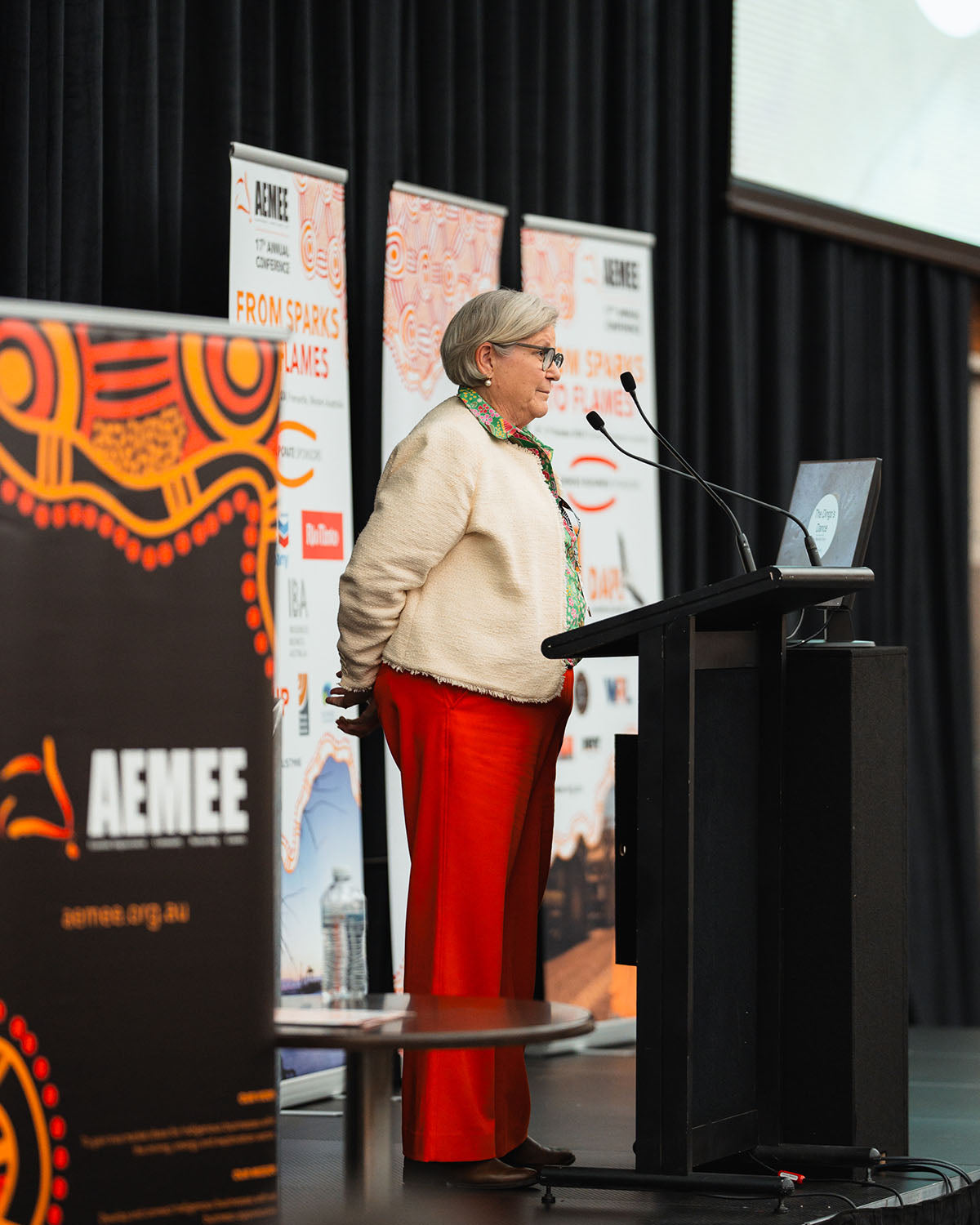 Keynote speaker Amanda Healy standing at the podium, sharing commercial growth milestones and corporate supply chain strategies with conference delegates.
