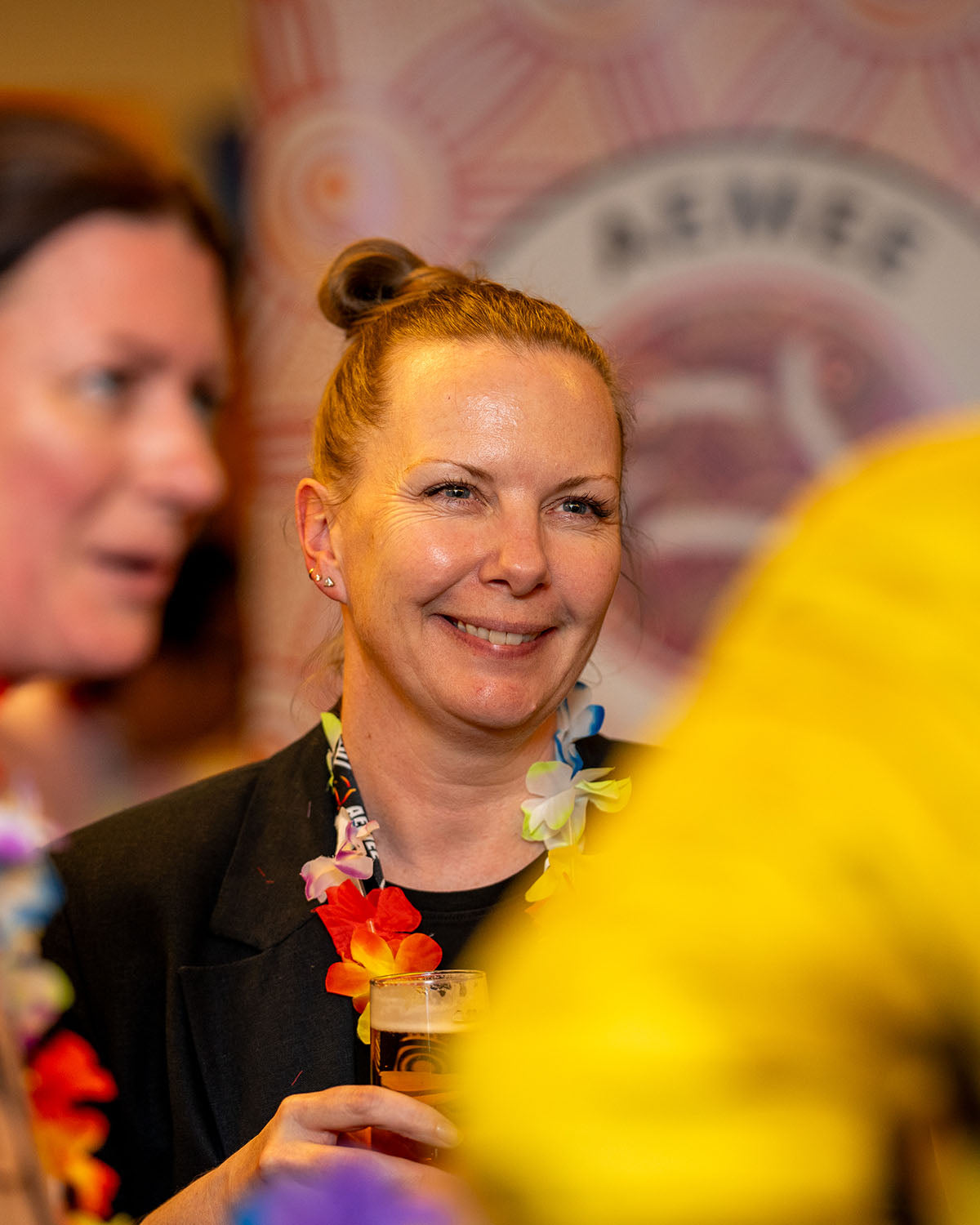 A close-up portrait of a female corporate delegate smiling and wearing a colourful tropical flower lei during the welcoming mixer at the AEMEE Networking Night.