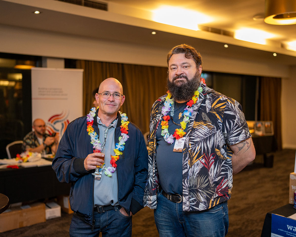 Djarindjin Aboriginal Corporation CEO Nathan McIvor, wearing a dark tropical palm-leaf shirt and flower lei, posing alongside a fellow delegate at the social mixer.
