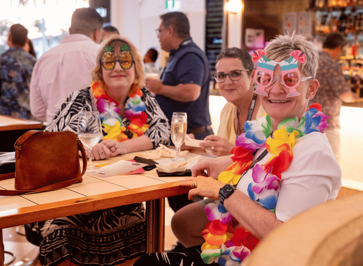 Delegates enjoying the AEMEE 2025 Annual Conference networking night in Darwin, wearing Hawaiian leis and novelty glasses. 