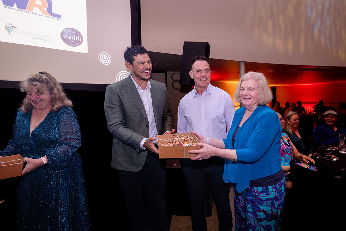 AEMEE conference presenters handing a gift box to a guest during the awards dinner.