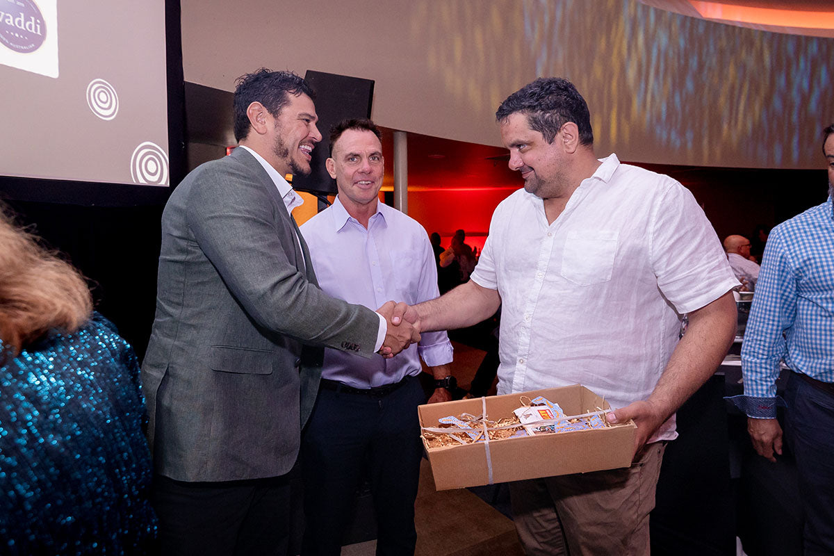 AEMEE conference presenter shaking hands with a guest holding a gift box during the awards dinner.