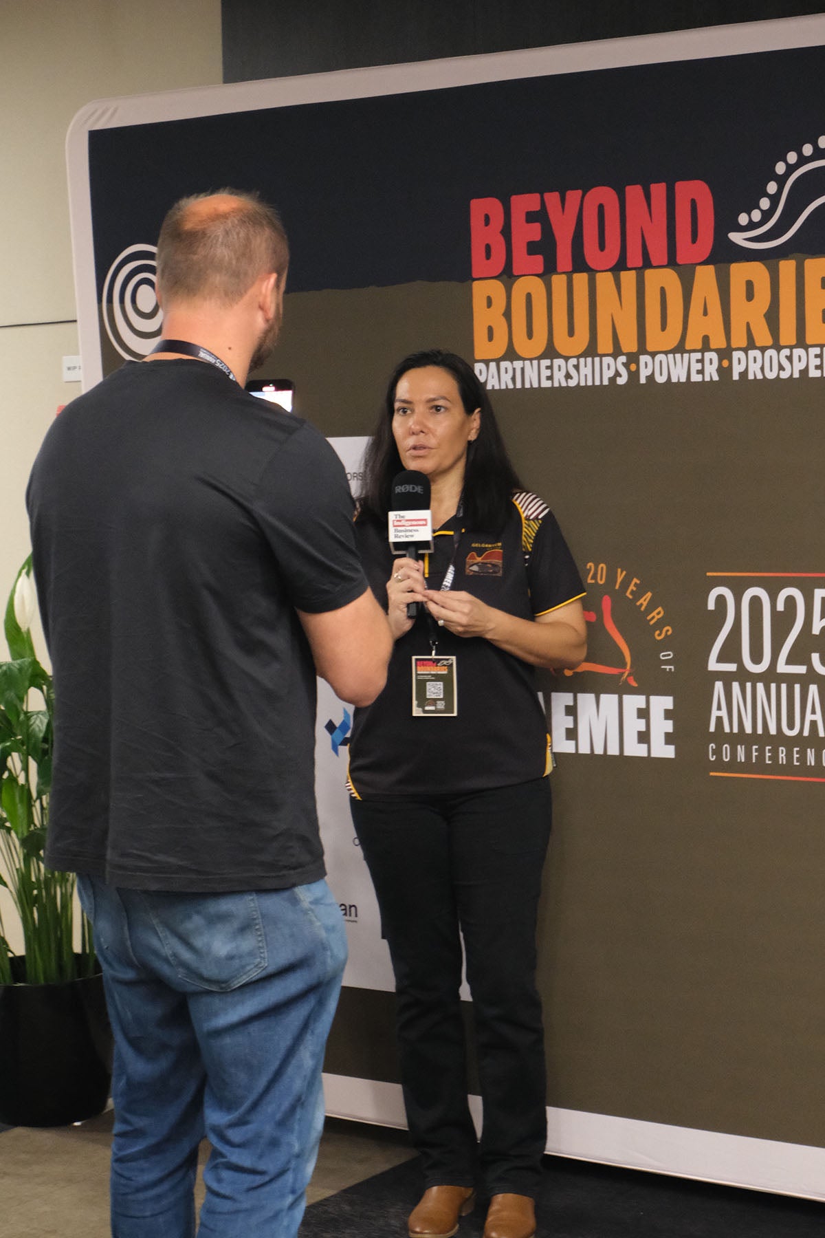 AEMEE conference attendee being interviewed in front of the 2025 Annual Conference branding wall.