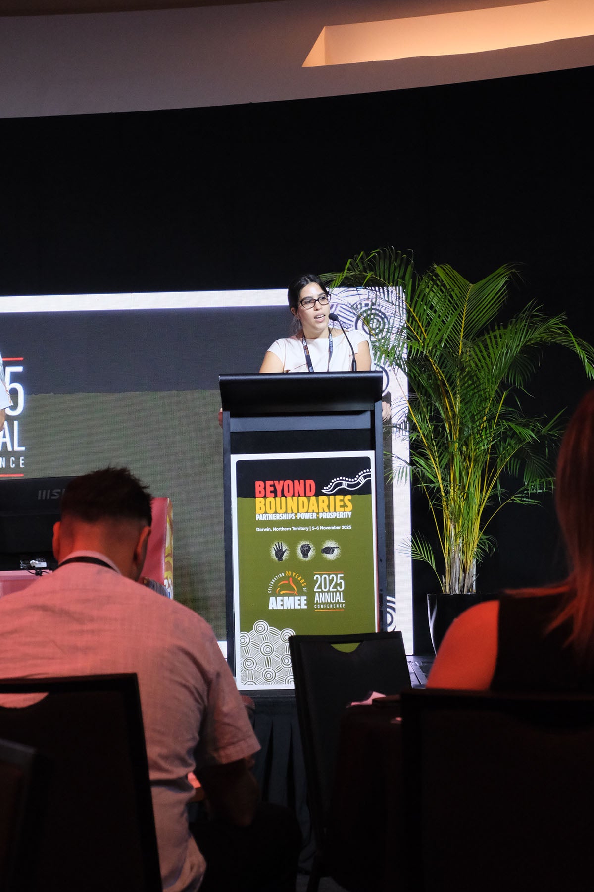 Speaker presenting at the AEMEE 2025 Annual Conference with Beyond Boundaries event branding on the podium.