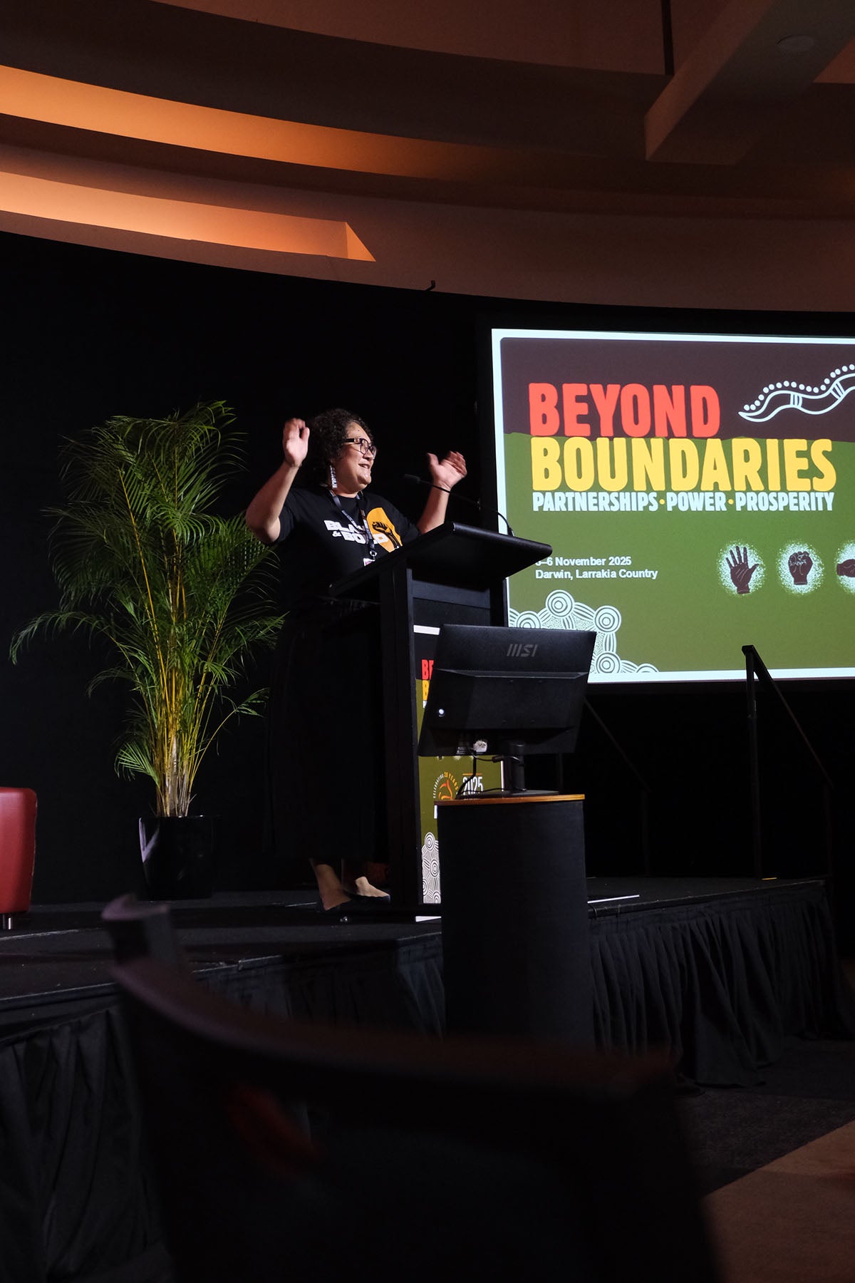 Speaker presenting at the AEMEE conference with Beyond Boundaries event branding behind them.